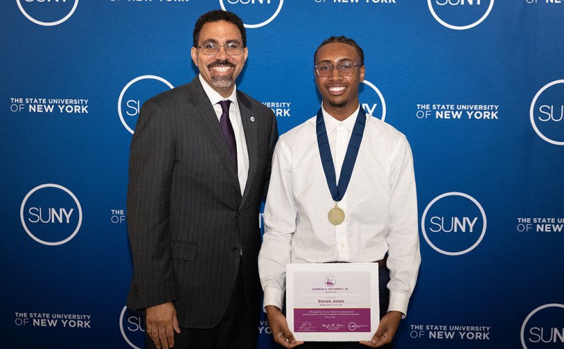 Steven Jones, estudiante de la Escuela de Administración, recibe el premio Norman R. a la excelencia estudiantil de manos del rector de SUNY, John King, en una ceremonia el 10 de marzo de 2026. McConey Jr. recibió el premio.