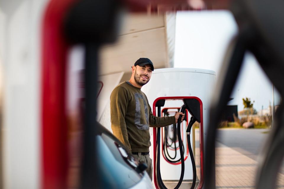 Un hombre carga su coche eléctrico.