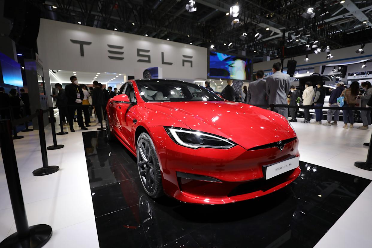 Un Tesla Model S rojo estacionado sobre azulejos negros durante una exhibición de autos