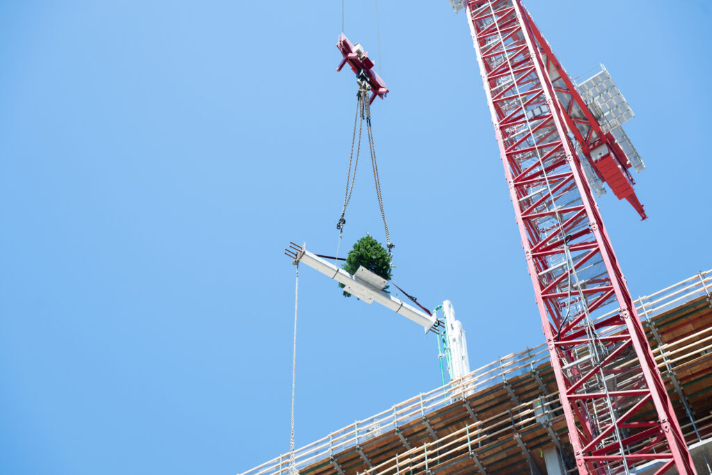 Los trabajadores de la construcción levantan una viga sobre el suelo con una grúa durante un evento de finalización en el sitio de construcción de People's Park, un hito importante en la construcción del proyecto.