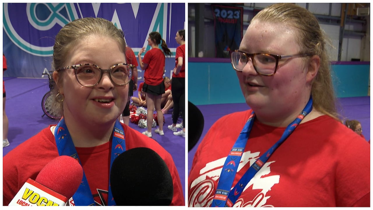 Dos mujeres con camisetas rojas están detrás de los micrófonos. Ambos llevan medallas de oro alrededor del cuello.