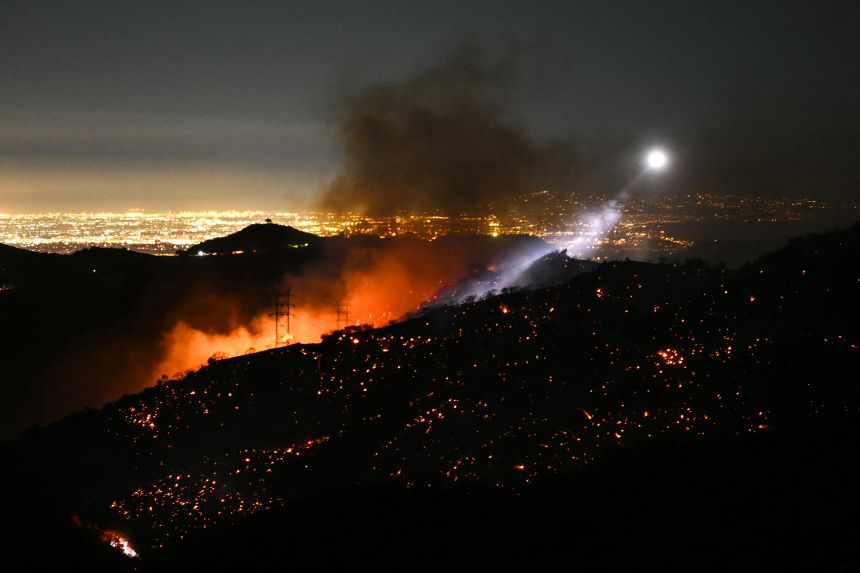 Las luces de los helicópteros de extinción de incendios iluminan una ladera llena de humo mientras el incendio Palisades crece cerca de Mandeville Canyon y Encino, California, el 11 de enero de 2025.