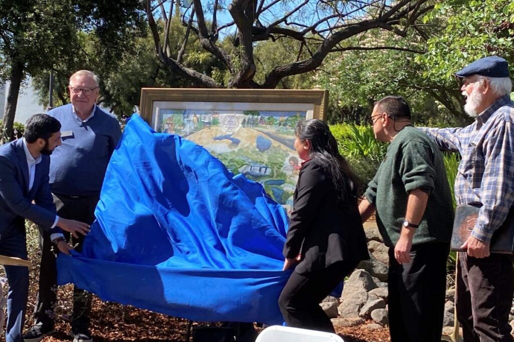 Los miembros de la junta de inauguración quitan un paño azul para revelar una acuarela de Nancy Pratt inspirada en el distrito de agua. Estefanía Uchida
