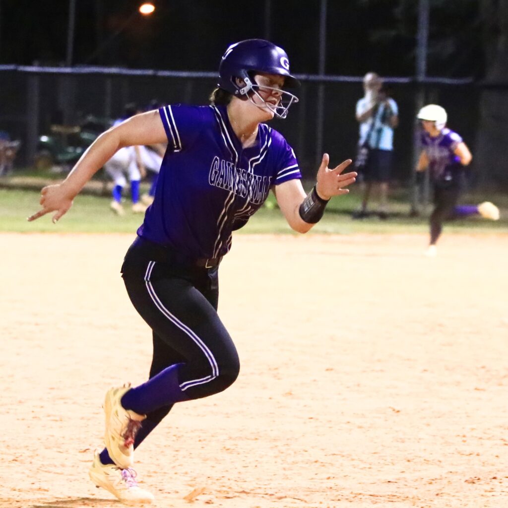 Adrianna Koralewski (16) de Gainesville conduce a casa para una ventaja de 6-4 en la sexta entrada contra Deltona en el juego de campeonato del Distrito 5A. Fotografiado por CJ Gish.