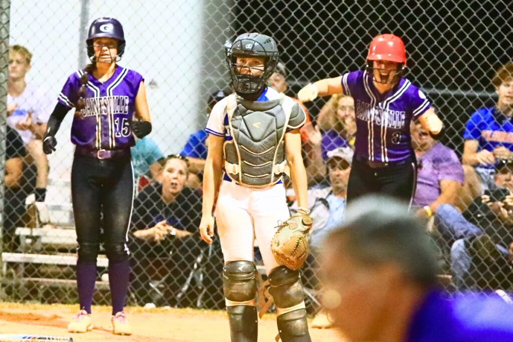 Lana Rennix (15) y Emma Burton (3) de Gainesville anotaron en la sexta entrada para una ventaja de 5-4 sobre Deltona en el juego de campeonato del Distrito 5A. Fotografiado por CJ Gish.